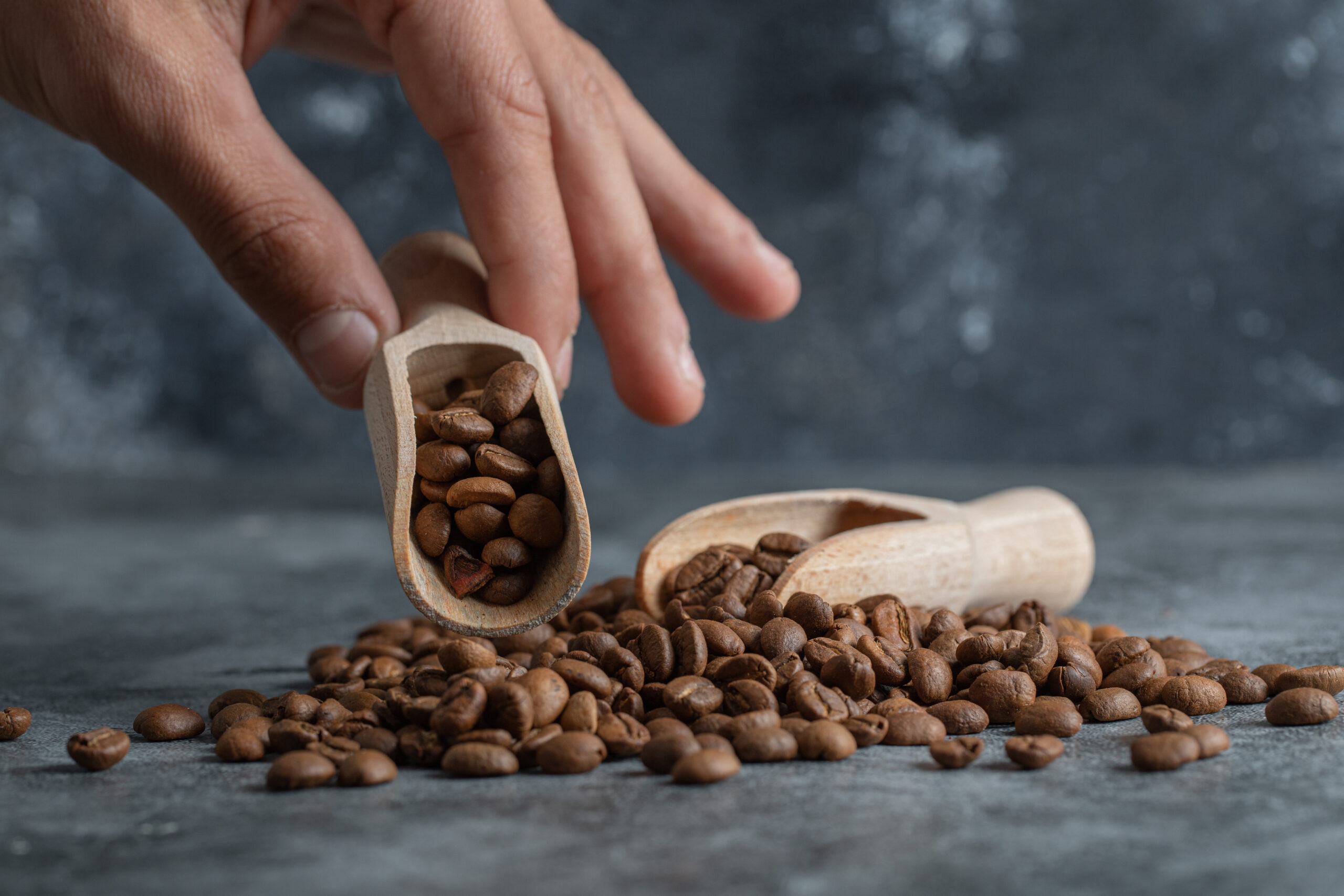 Hand holding a wooden spoon with coffee beans