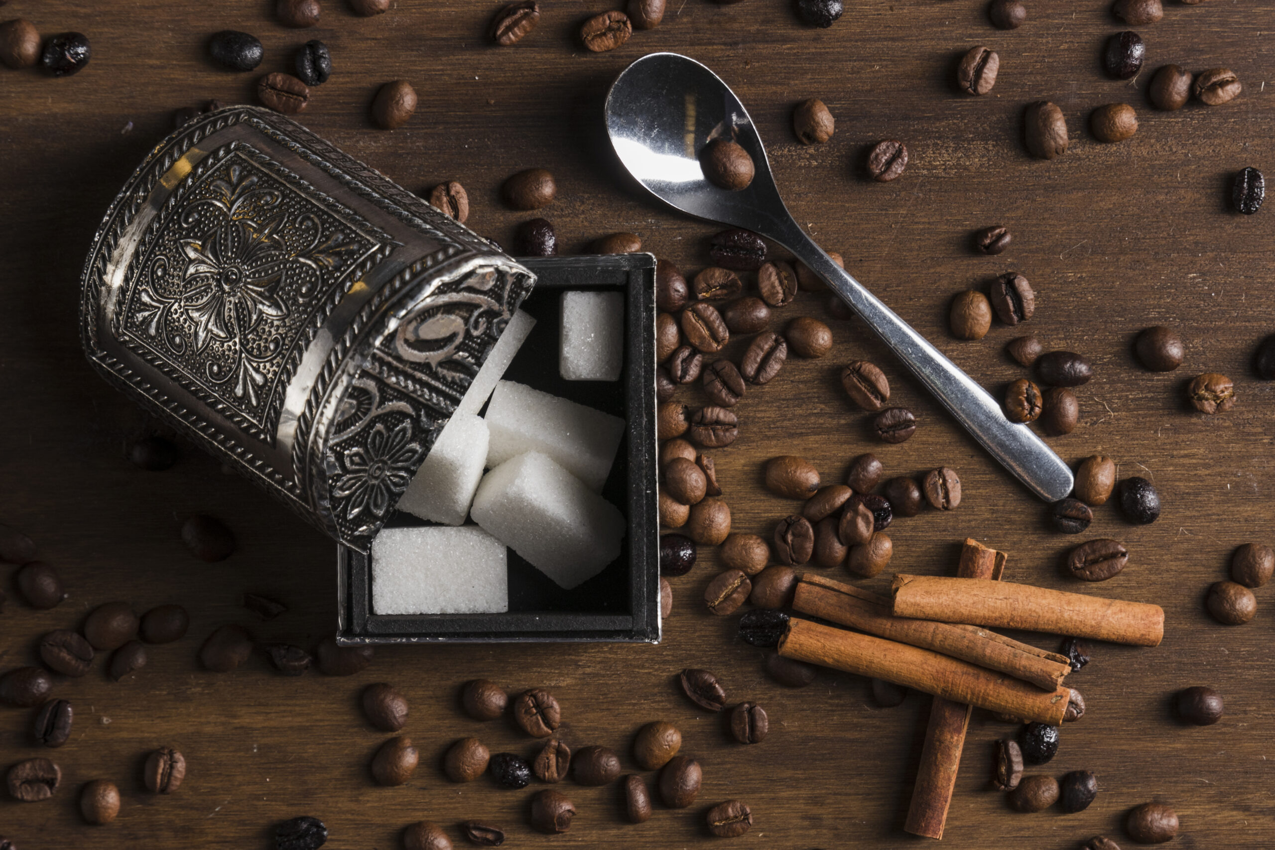 sugar-bowl-near-cinnamon-sticks-spoon-coffee-beans