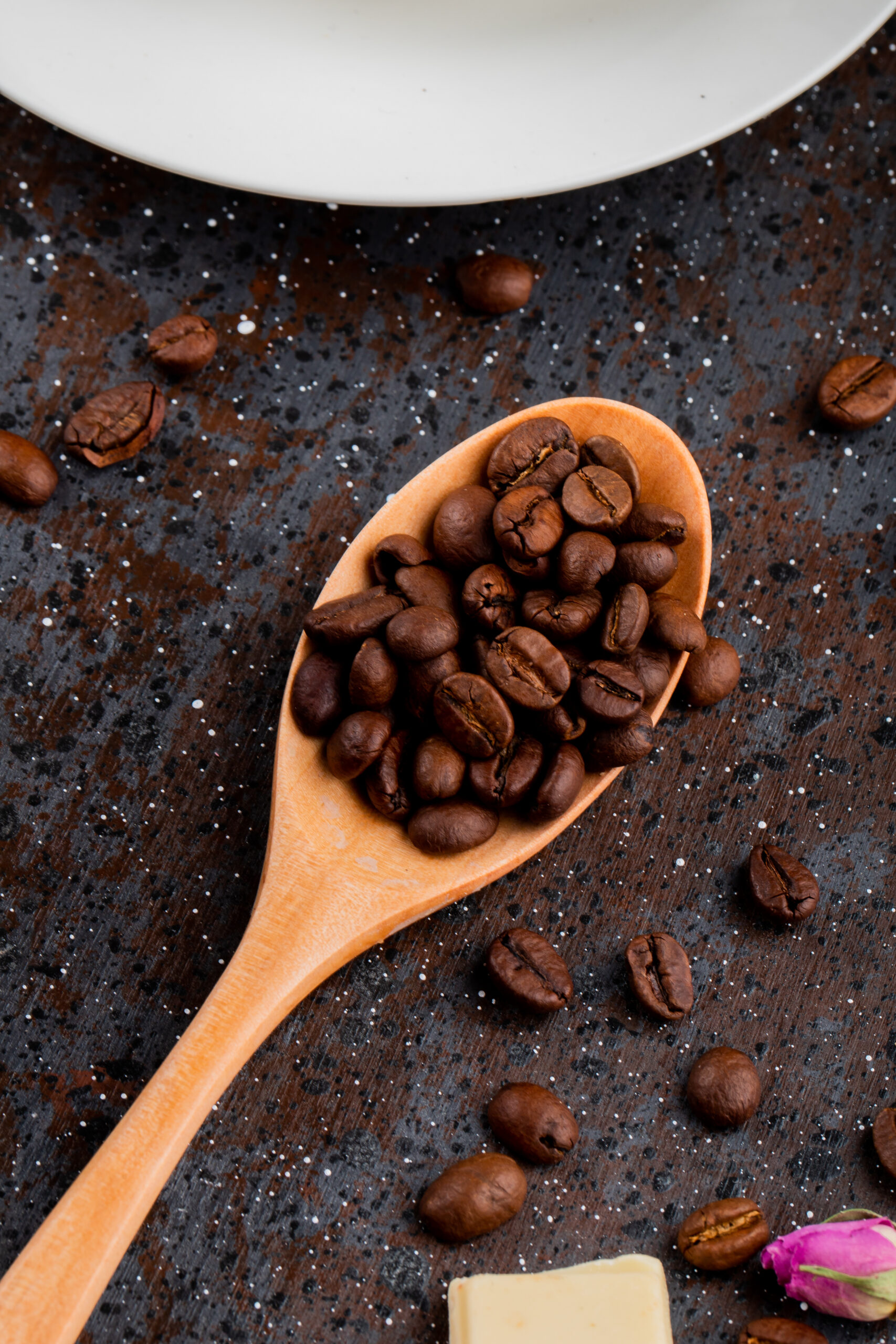 top view of a wooden spoon with coffee beans on black background