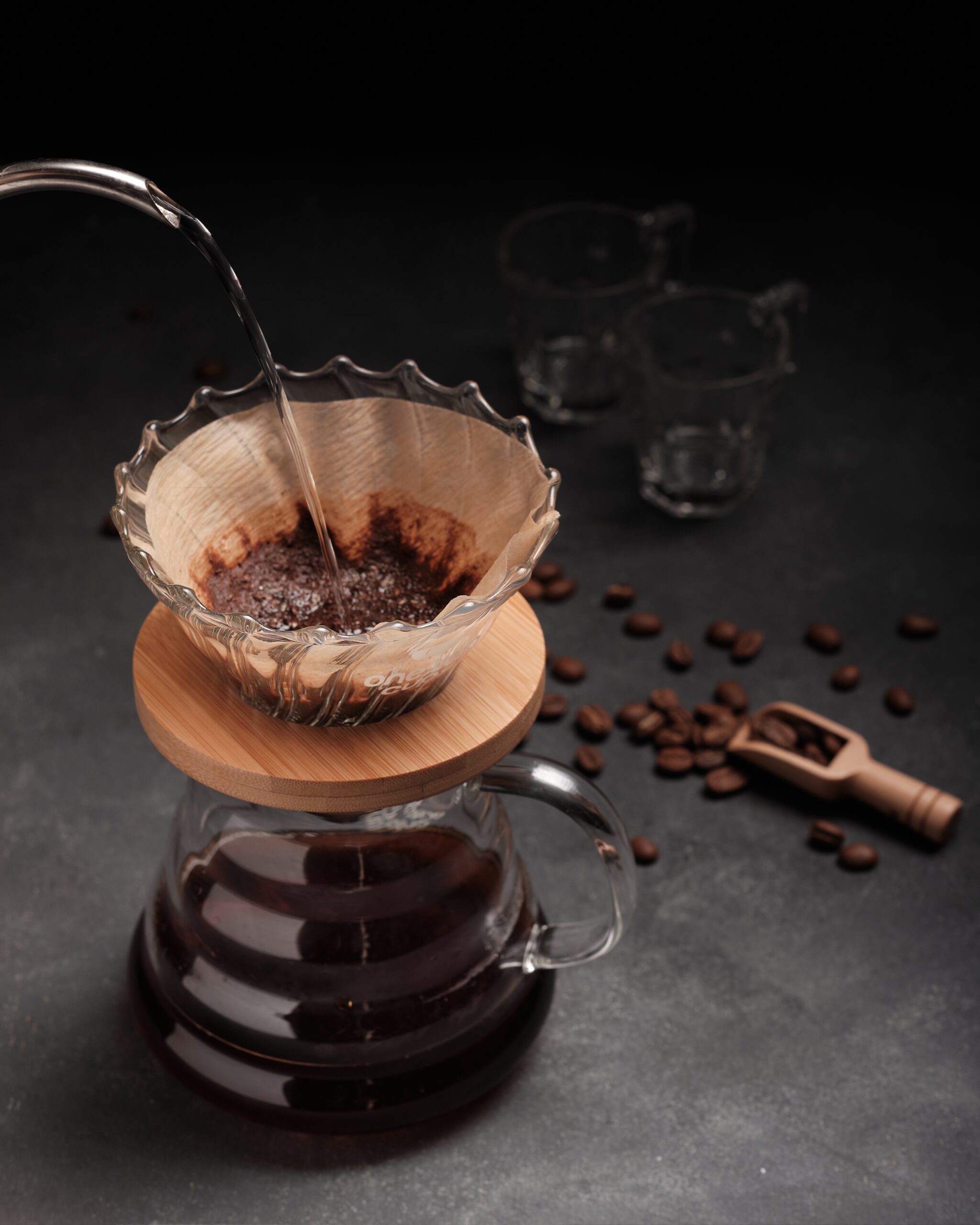 Vertical shot of a person pouring coffee in glass on a black background